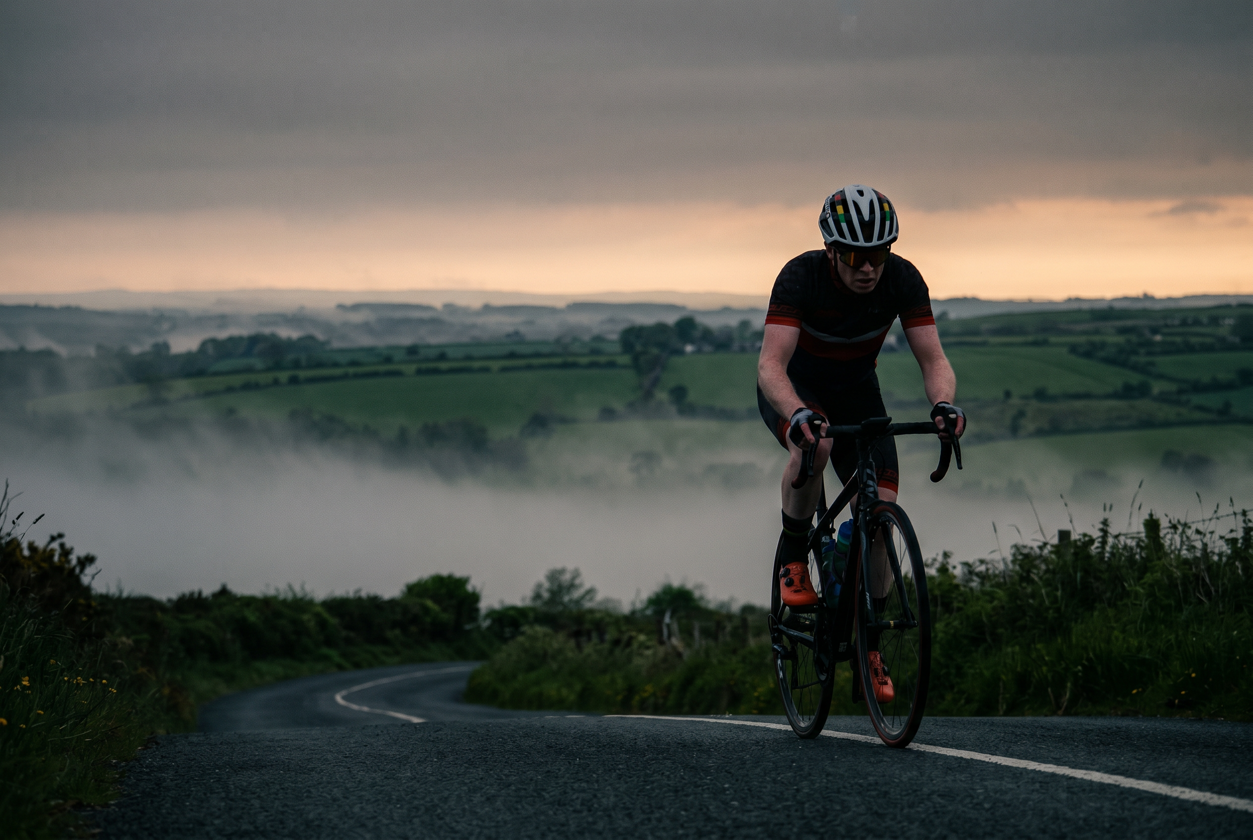 Cyclist climbing Irish hill at dawn